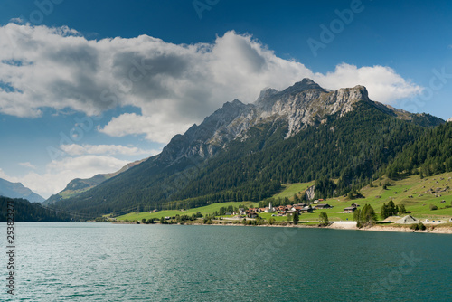 view of an idyllic and picturesque turquoise mountain lake surrounded by green forest and mountain peaks in the Swiss Alps