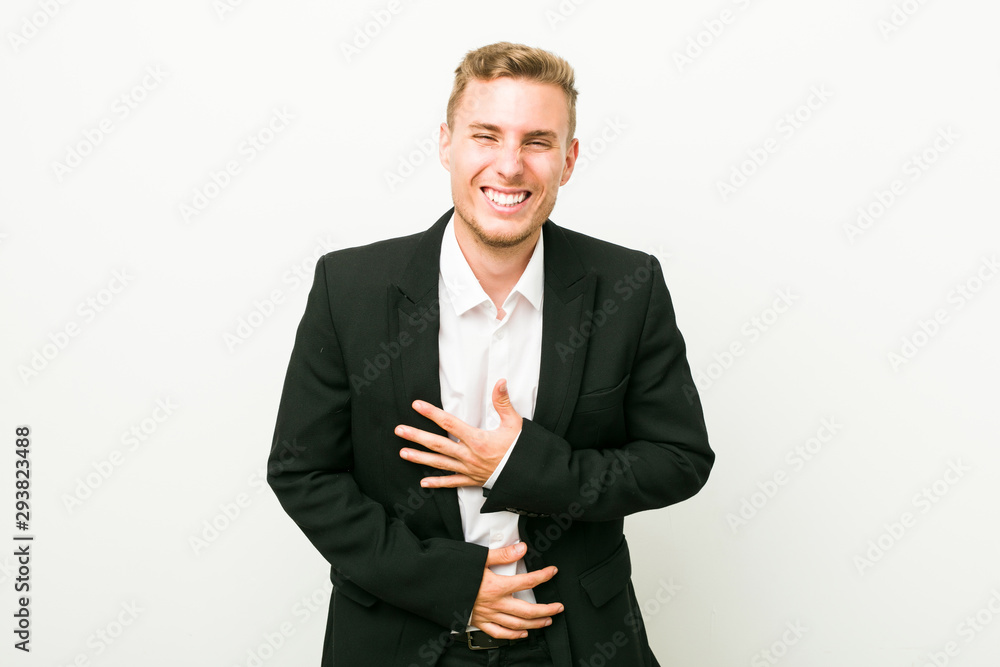 Young caucasian business man laughs happily and has fun keeping hands on stomach. Young caucasian business man laughs happily and has fun keeping hands on stomach.