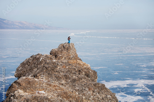 Traveler on top of the Oltrek island cape Lake Baikal. Winter landscape photo