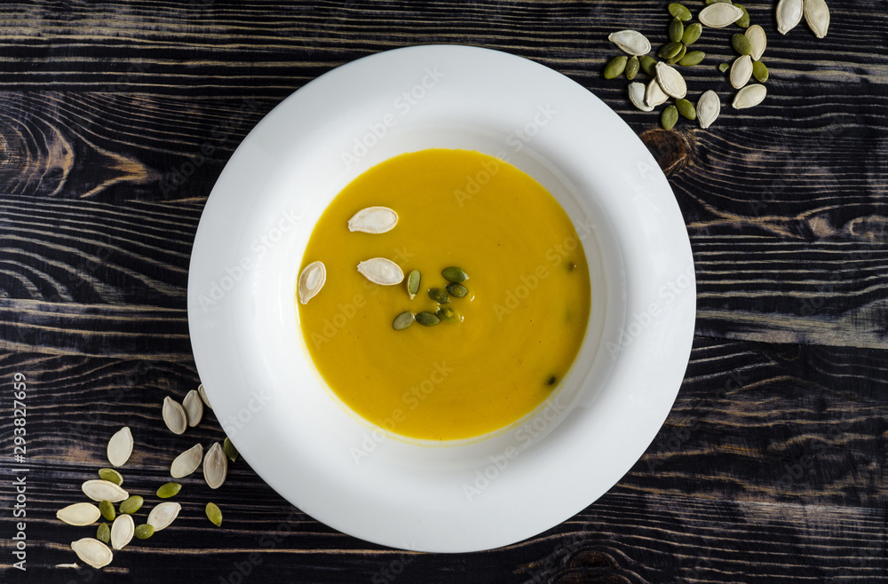 pumpkin soup in white plate natural wood dark background top view pumpkin soup in white plate natural wood dark background top view