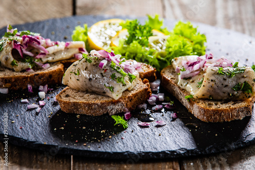 Marinated herring fillets on slices of bread on black stone