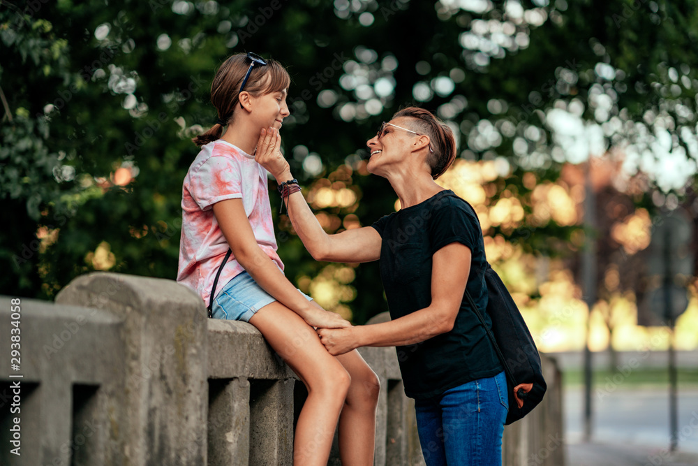 Mother talking with daughter sitting at the fence Mother talking with daughter sitting at the fence