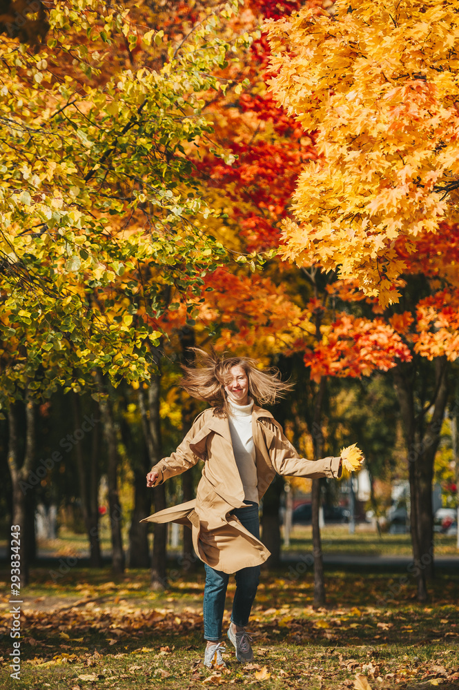 Beautiful girl in baege coat jumping in autumn park. Beautiful girl in baege coat jumping in autumn park.