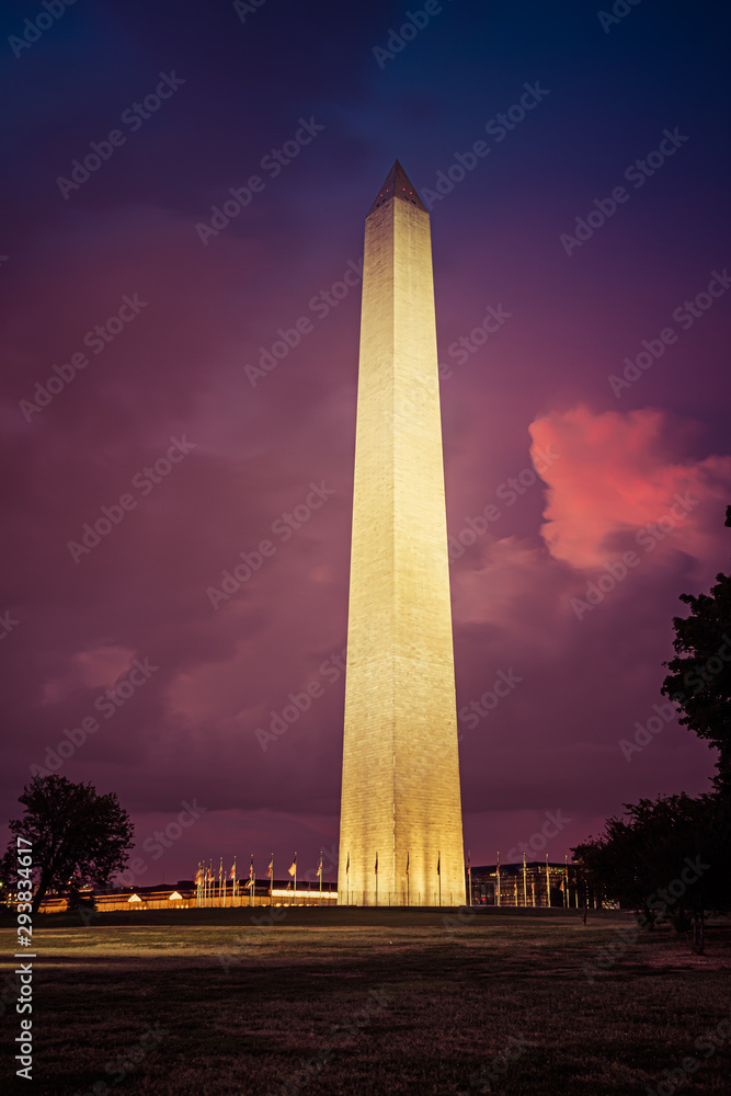 The Washington Monument lit up under colorful evening clouds.