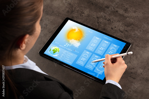 Business woman checking weekly weather forecast on tablet