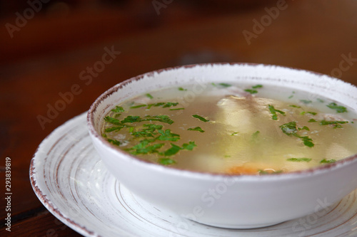 chicken soup in white plate on wooden background