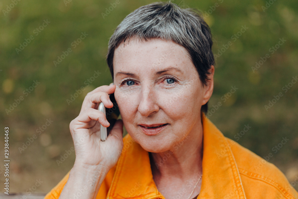 Portrait of a beautiful senior woman. Happy senior woman on the city streets using cellphone. Portrait of a beautiful senior woman. Happy senior woman on the city streets using cellphone.