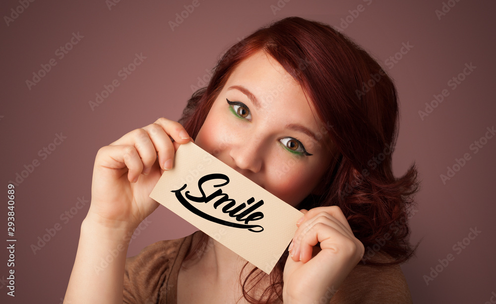 Person holding card with smile in front of her mouth Person holding card with smile in front of her mouth