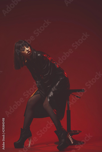 Fotografía Attractive young woman in black leather coat and stockings on black shoes alluring posing
