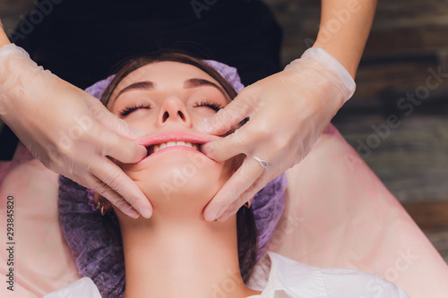 cosmetologist makes a buccal massage of the patient's facial muscles.