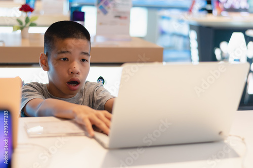 Disabled child on wheelchair trying to use a computer with excitement in an IT shop , Special children's lifestyle, Life in the education age of special need kids, Happy disability kid concept.