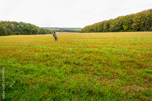 Lady stands in a field during a cloudy  cold and humid autumn day.
