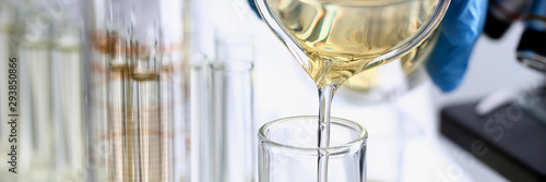 Male hand hold yellow liquid in test tube. Conveyor line production household cleaning products detergents help cleaning destruction stains pests urine poison antidote vaccine concept.