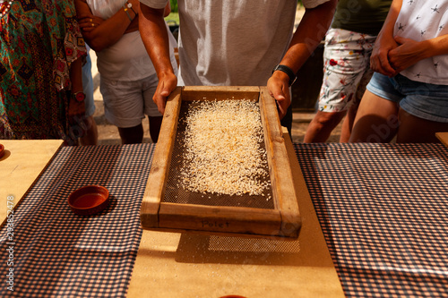 Fotografie farmer filtering rice grains with old traditional strainer on table, showing old