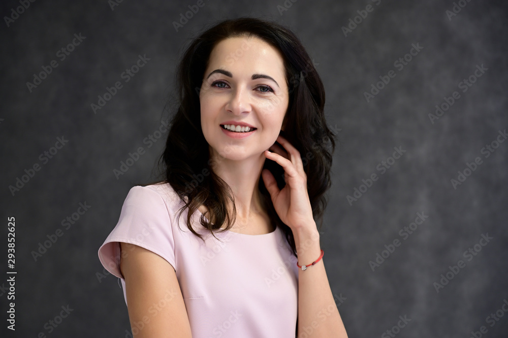 Close-up portrait of an adult pretty brunette woman in a pink t-shirt on a gray background in the studio. Beauty, Art, model posing. Close-up portrait of an adult pretty brunette woman in a pink t-shirt on a gray background in the studio. Beauty, Art, model posing.