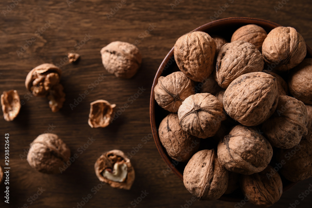 Walnuts nuts in a bowl on a dark brown wooden background in a dark key Walnuts nuts in a bowl on a dark brown wooden background in a dark key