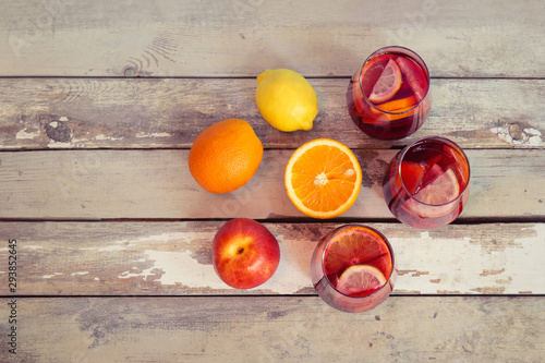 Red wine sangria with fruits in glasses and fresh fruits near on aged wooden background. Copy space, top view.