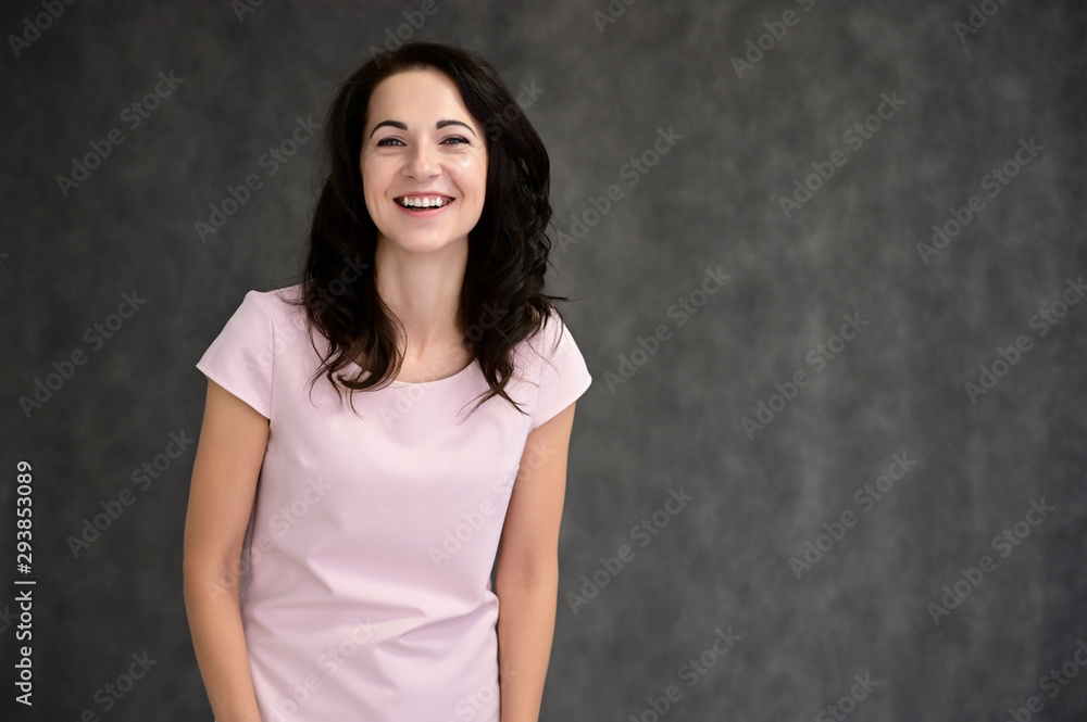 Close-up portrait of an adult pretty brunette woman in a pink t-shirt on a gray background in the studio. Beauty, Art, model posing. Close-up portrait of an adult pretty brunette woman in a pink t-shirt on a gray background in the studio. Beauty, Art, model posing.