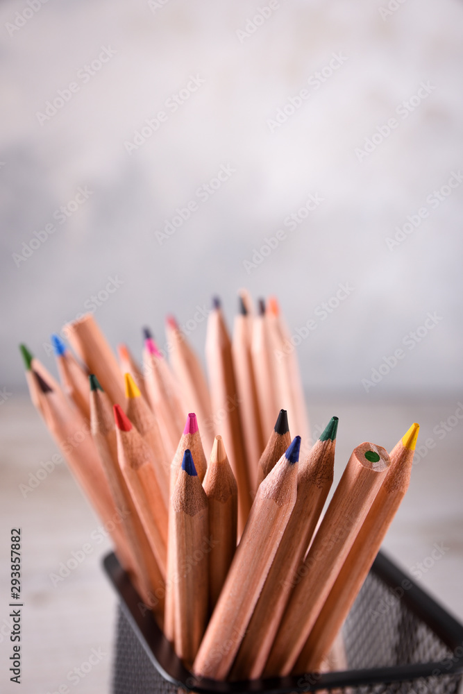 Group of school supplies pencils and books on wooden table over a grey background Group of school supplies pencils and books on wooden table over a grey background