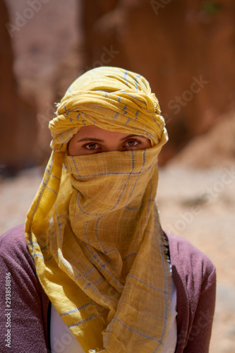 Portrait of the female tourist with a tied yellow berber tagelmust scarf. 