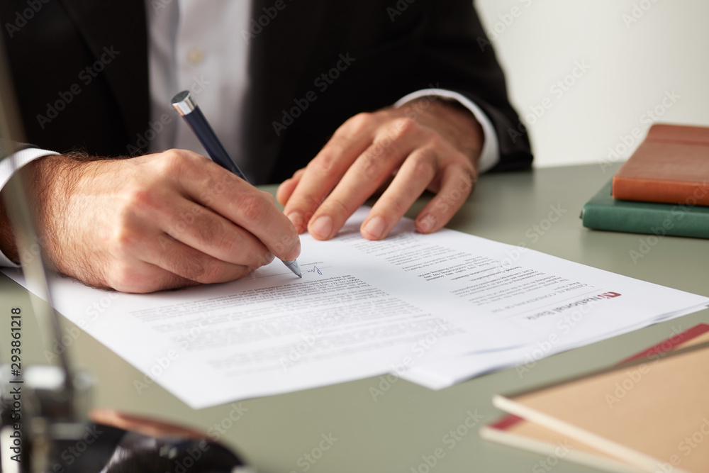 Faceless formal man signing documents Faceless formal man signing documents