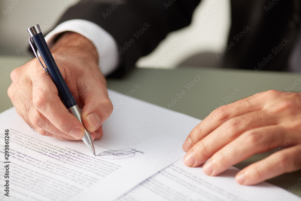 Businessman putting signature on agreement paper Businessman putting signature on agreement paper