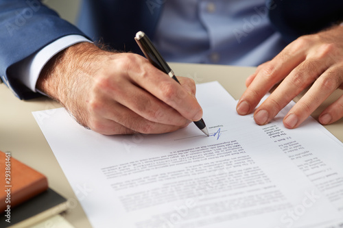 Faceless man signing paper photo