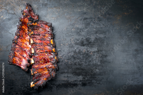 Barbecue burnt chuck beef ribs with hot marinate as top view on an old rustic board with copy space right