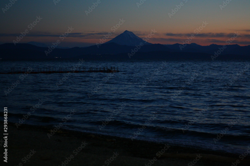 Sunset and twilight in, Kamchatka peninsula, Russia. Blue water of the ocean and mountains in horizon.