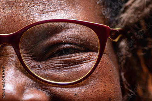 Canvastavla An extreme closeup view on the eye of an elderly African woman wearing reading glasses, jovial and smiling wise old woman in close-up detail