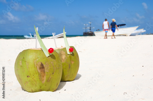 Coconut drink on beach, unrecognizable people walking along sea shore in the background, Punta Cana, Dominican Republic