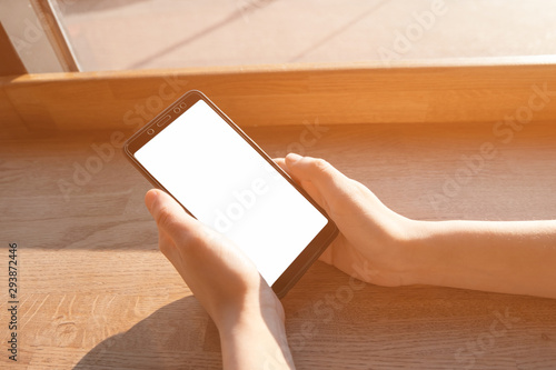 Closeup image of a woman's hand holding smartphone with blank screen. Mockup ready for text message or content. Hands girl with a mobile phone. Blank display. Empty display.