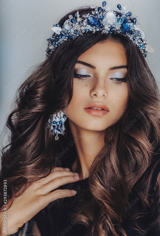 Fototapeta premium Portrait of beautiful brunette woman in crown with makeup in fashion black clothes