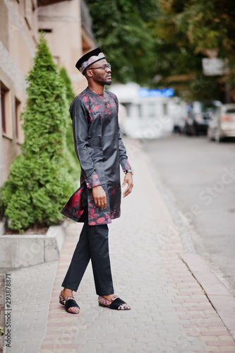 Handsome afro american man wearing traditional clothes, cap and eyeglasses in modern city.