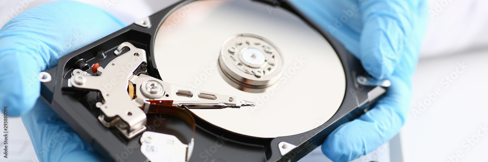 A male repairman wearing blue gloves is holding a hard drive from computer or laptop in hands. Performs fault diagnostics and performs urgent repairs recovery of lost data during deletion HDD closeup A male repairman wearing blue gloves is holding a hard drive from computer or laptop in hands. Performs fault diagnostics and performs urgent repairs recovery of lost data during deletion HDD closeup