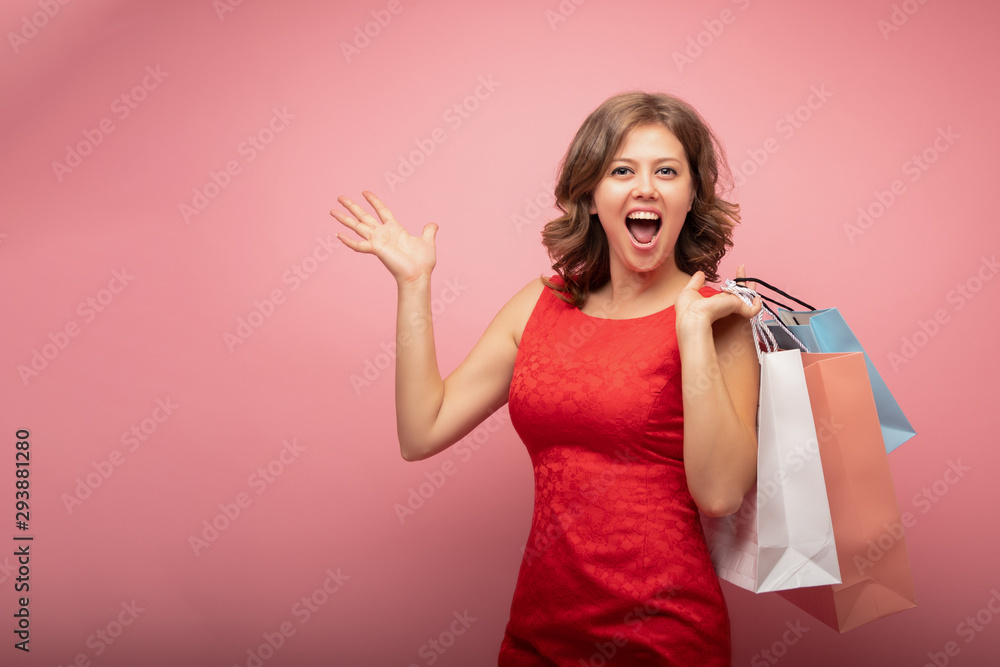 Buy and sell concept of happy young girl in red dress with bags on pink background Buy and sell concept of happy young girl in red dress with bags on pink background