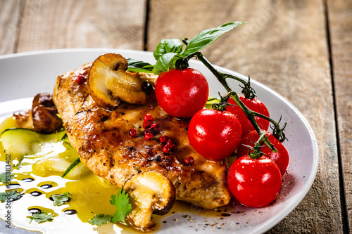 Grilled chicken fillet and vegetables on white plate