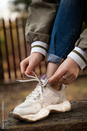 girl knits shoelaces on sports sneakers. Outdoor sports.