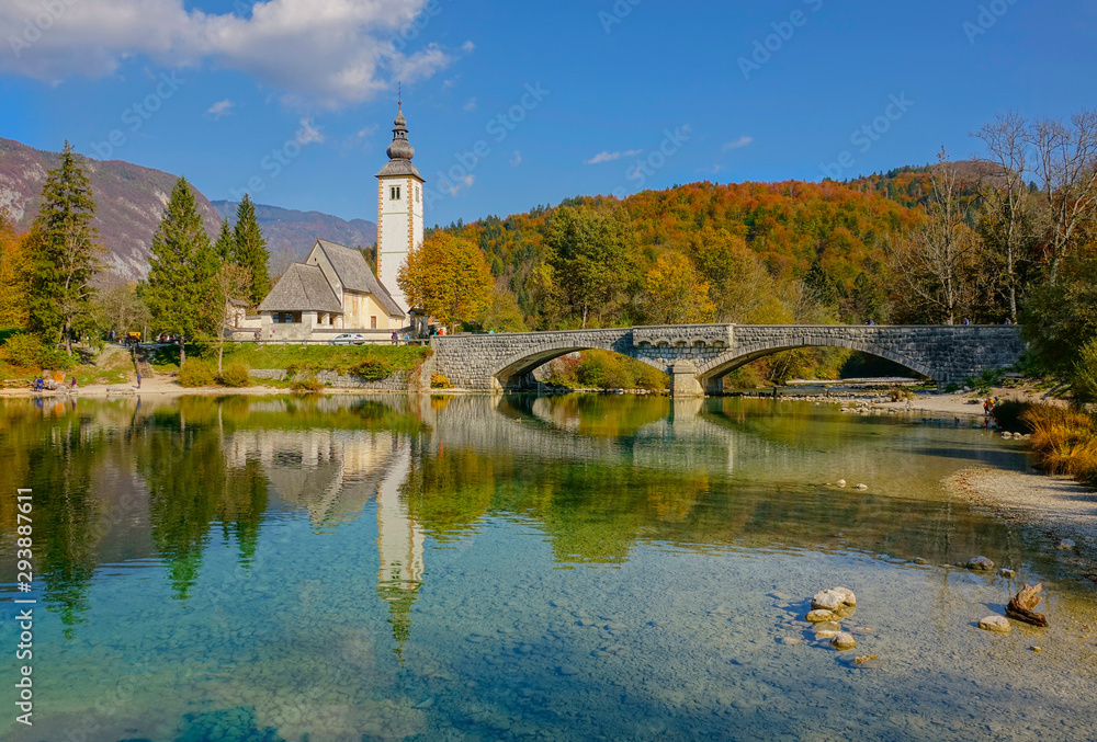 Scenic shot of an old church by the beautiful emerald colored lake Bohinj.