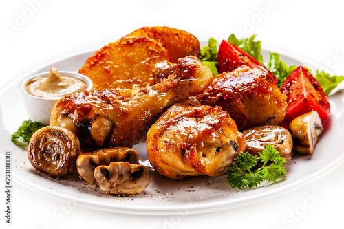 Grilled chicken drumsticks with baked potatoes and vegetables