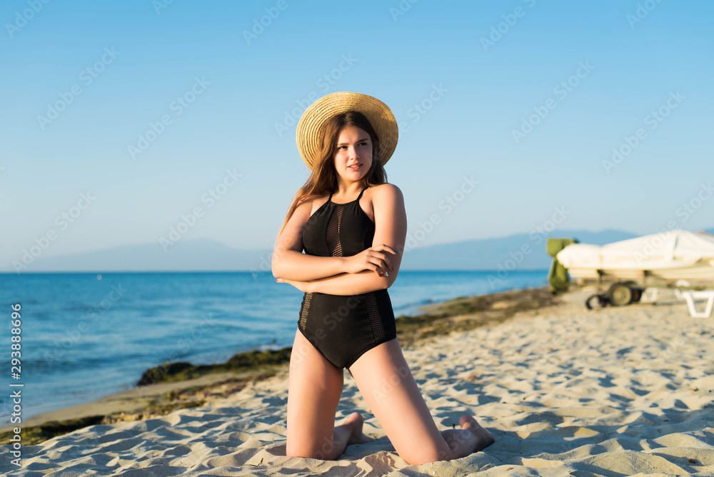 Cheerful plus size teenage girl wearing hat enjoying the beach. smiling, happy, positive emotion, summer style.