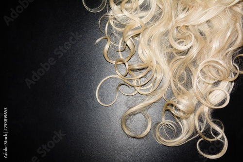 white curly hair on a black background. blonde wig. top view background
