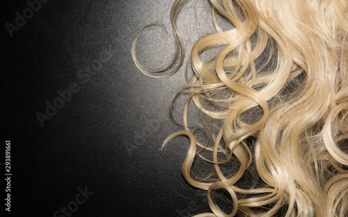 white curly hair on a black background. blonde wig. top view background