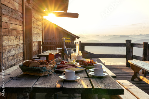 Breakfast table in rustic wooden terace patio of a hut hutte in Tirol alm at sunrise photo