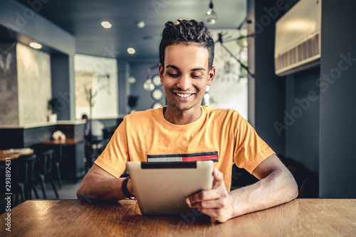 Indian young man using tablet in a beautiful cafe.