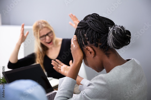 Fototapeta Naklejka Na Ścianę i Meble -  African Woman Sitting In Front Of Female Boss Blaming Her