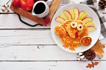 Thanksgiving breakfast with turkey pancakes. Top view corner border against a white wood background with copy space.