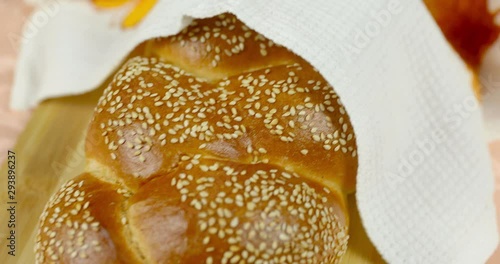 The camera moves smoothly to the Shabbat challah lying on a cutting board on a tablecloth covered with a white towel