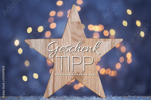 Text Geschenktipp vor Holzstern und leuchtendem Hintergrund photo