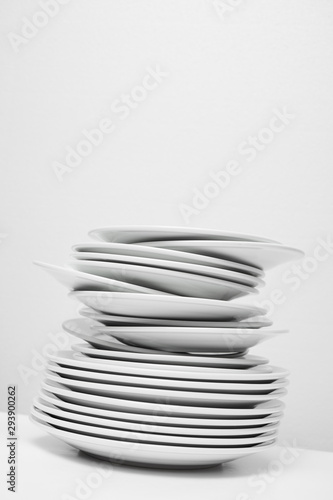 messy stack of white plates about to fall, isolated on white